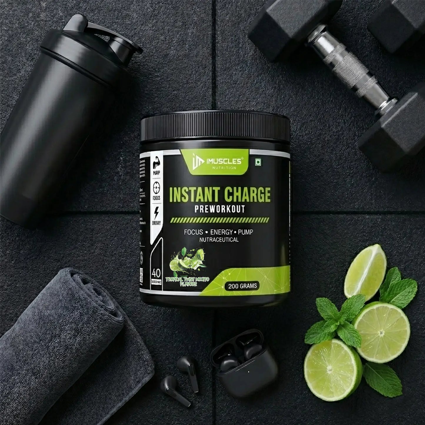 A top-down premium flat lay photography image labeled "Tropical Twist Mojito 13.jpg" featuring an iMuscles Nutrition "INSTANT CHARGE" pre-workout jar in the center. The jar is arranged on a textured black gym mat alongside a black shaker bottle, a dumbbell, a rolled grey gym towel, wireless earbuds, fresh lime slices, and mint leaves.