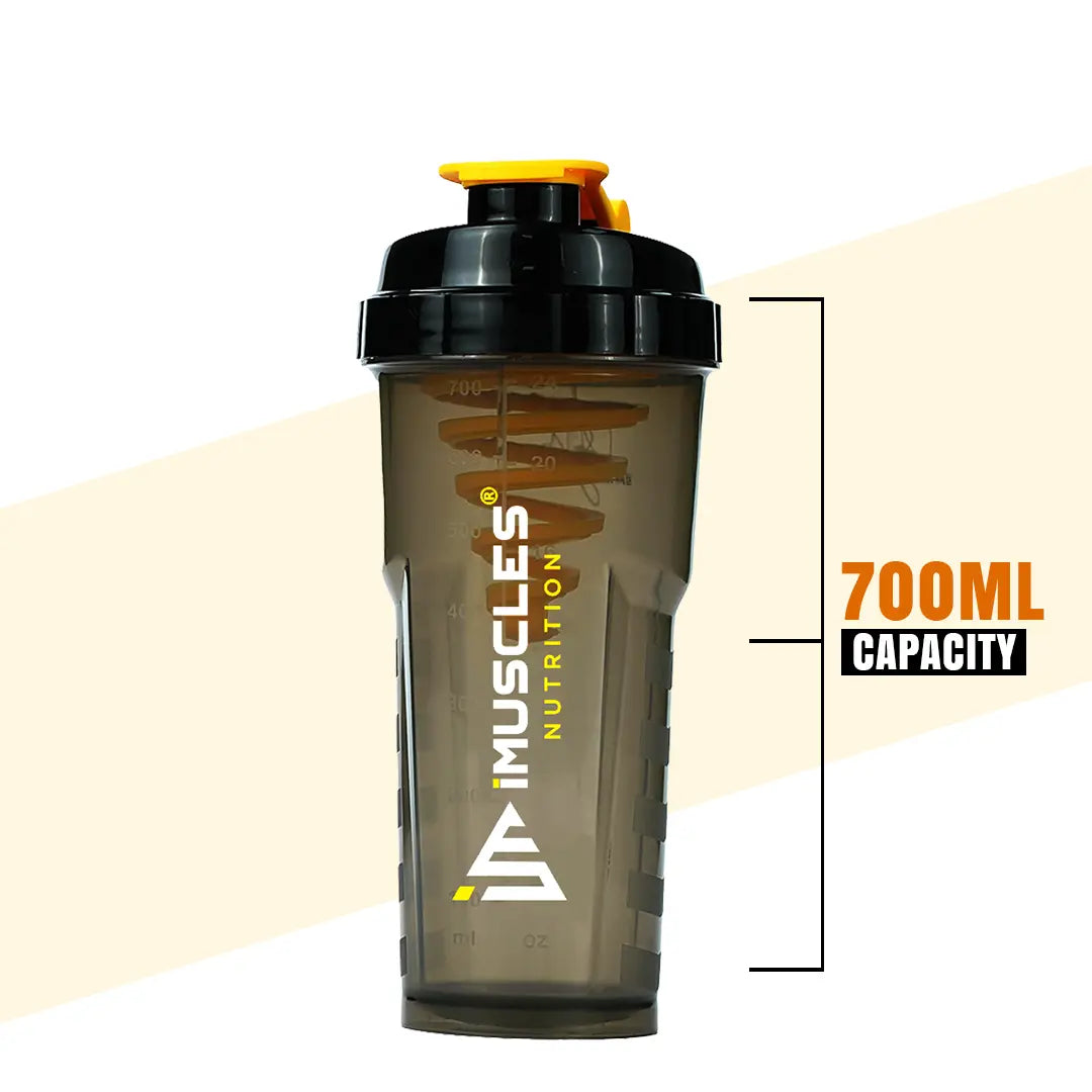 A promotional banner for iMuscles Nutrition, referenced as 7.1.jpg. The left side features bold text reading "LOVED AND RECOMMENDED BY THOUSANDS" followed by the tagline "Fuel Your Fitness. Shake Smarter With iMuscles." The right side shows a collage of lifestyle settings, with the central focus on a sleek, dark translucent iMuscles shaker bottle resting on a gym bench. Other background elements include a home office setup and a yoga mat with a bowl of fruit.