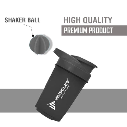 A promotional banner for the iMuscles Nutrition black shaker bottle titled black 1.png. On the left side, bold dark gray text on a light gray background reads "SHAKE UP SUCCEED" and "YOUR FITNESS GAME CHANGER". The right side features a 500 ml sleek black shaker bottle and a matching black mixing ball, labeled with "VERSATILITY" and "500 ML