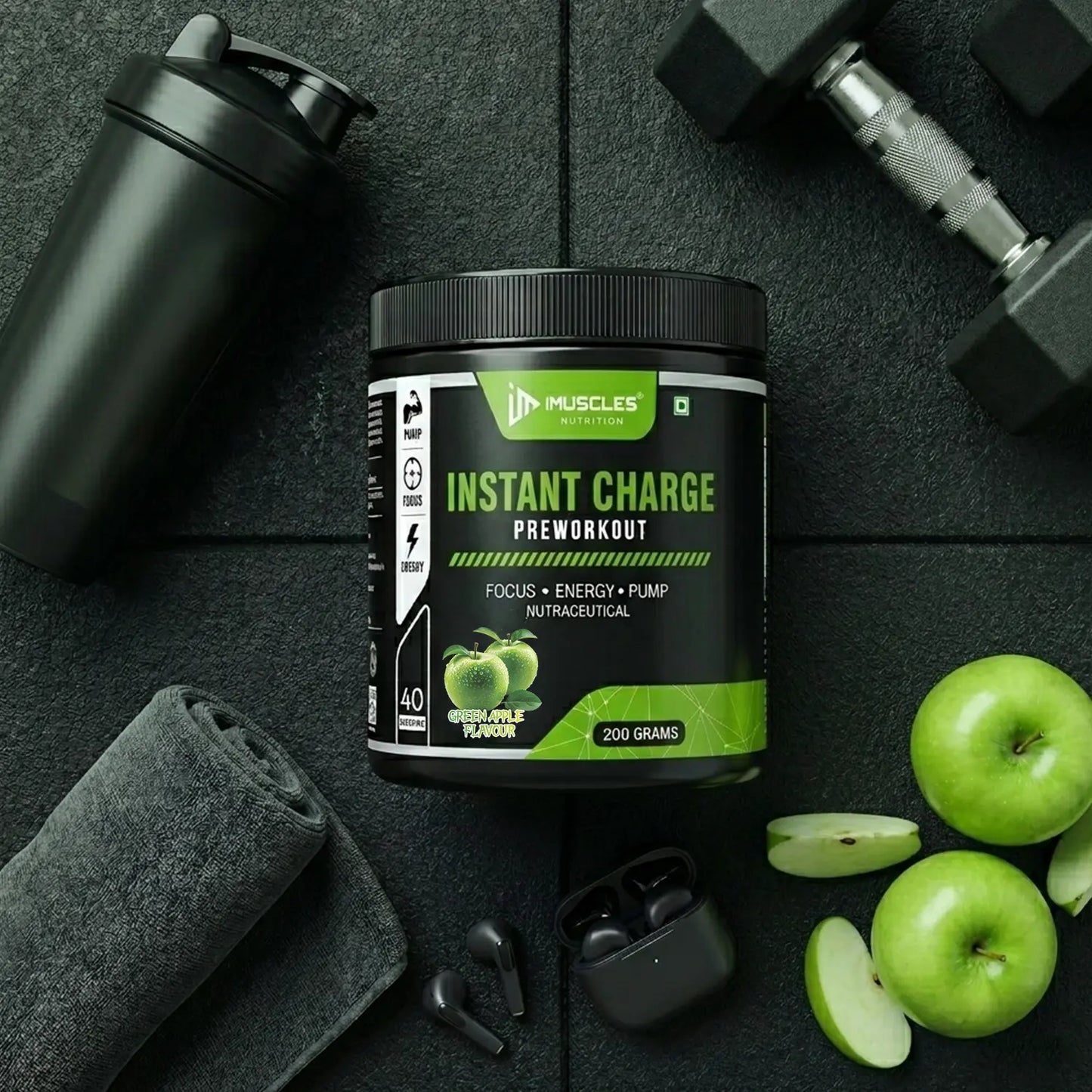 A top-down premium flat lay photography image labeled "Green Apple 13.jpg" featuring an iMuscles Nutrition "INSTANT CHARGE" pre-workout jar in Green Apple flavour at the center. The black jar is arranged on a textured black gym mat alongside a black shaker bottle, a dumbbell, a rolled grey gym towel, wireless earbuds, whole green apples, and fresh apple slices.