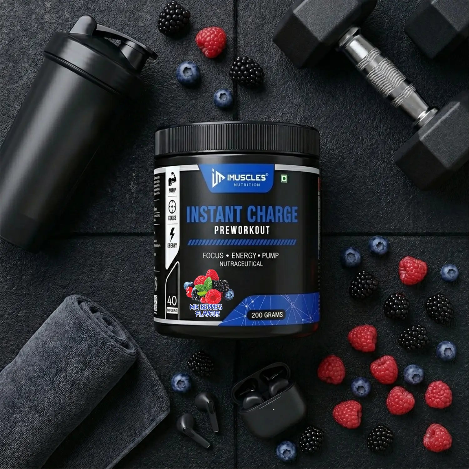 A square digital product promotional image titled "Mix Berries 13.jpg" featuring an iMuscles Nutrition "INSTANT CHARGE" pre-workout jar centered on a dark gym floor. The scene is accessorized with a black shaker, a gym towel, dumbbells, and wireless earbuds, all surrounded by scattered fresh raspberries, blackberries, and blueberries.